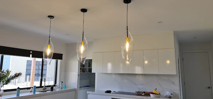 Three glass pendant lights installed over a kitchen island bench