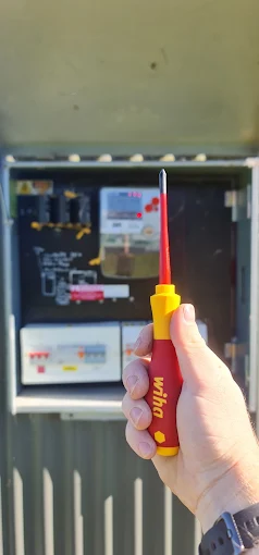 Electrician testing a switchboard with an insulated screwdriver